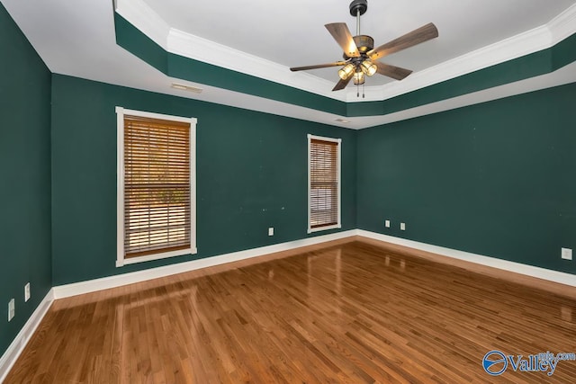 unfurnished room featuring a raised ceiling, hardwood / wood-style flooring, and ornamental molding