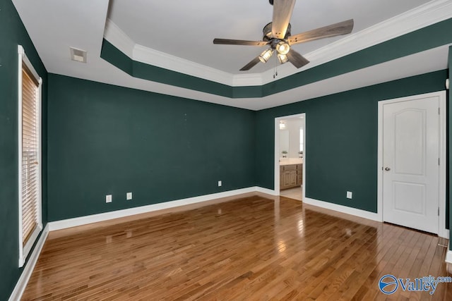 unfurnished bedroom with ceiling fan, wood-type flooring, crown molding, and a tray ceiling