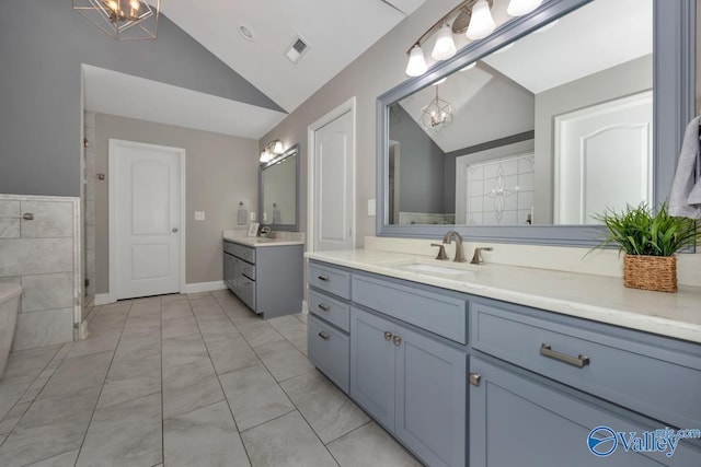 bathroom featuring vanity, an inviting chandelier, vaulted ceiling, and walk in shower