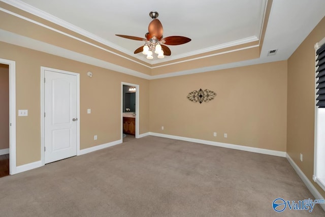 carpeted spare room with ceiling fan, ornamental molding, and a tray ceiling