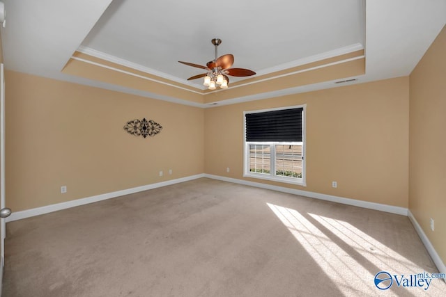 carpeted spare room with a tray ceiling, ceiling fan, and crown molding