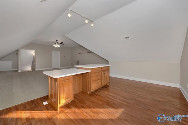 interior space featuring ceiling fan, rail lighting, lofted ceiling, and light wood-type flooring