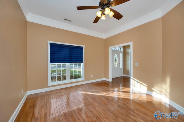 spare room featuring crown molding, ceiling fan, a healthy amount of sunlight, and wood-type flooring