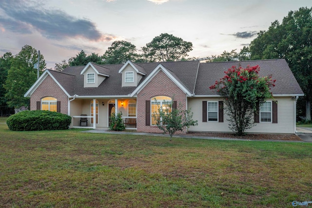 cape cod house with a porch and a lawn