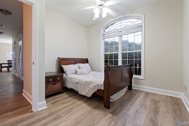 bedroom with light hardwood / wood-style floors, vaulted ceiling, and ceiling fan