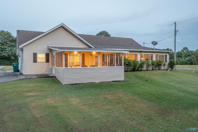 back of house with a sunroom and a lawn