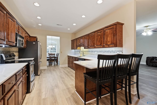 kitchen featuring stainless steel appliances, light stone countertops, sink, and a breakfast bar area