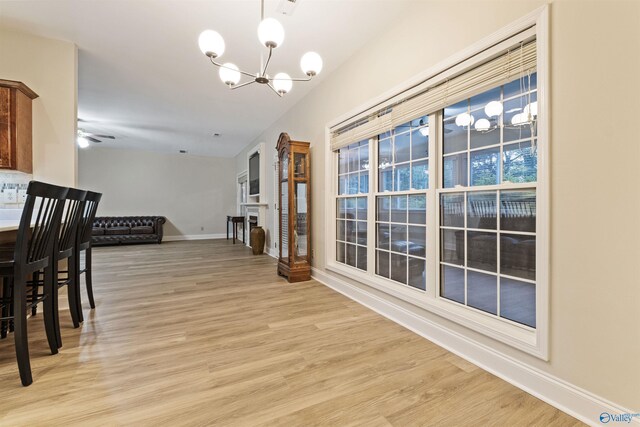 dining area with ceiling fan with notable chandelier and light hardwood / wood-style floors