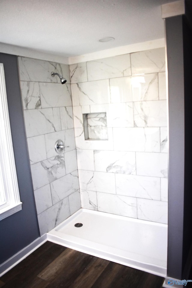 bathroom with hardwood / wood-style flooring and tiled shower