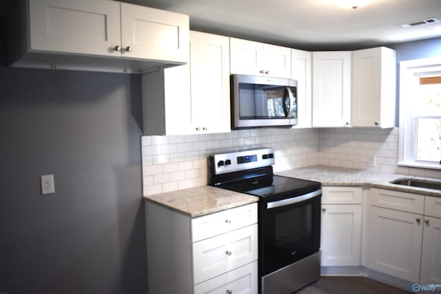 kitchen featuring white cabinetry, appliances with stainless steel finishes, and tasteful backsplash