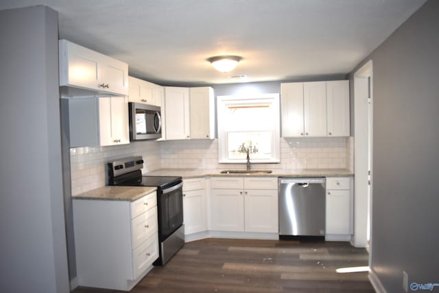 kitchen with decorative backsplash, stainless steel appliances, dark wood-type flooring, sink, and white cabinets