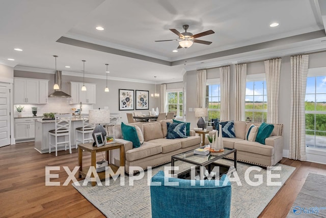 living room featuring ornamental molding, a raised ceiling, ceiling fan, and light hardwood / wood-style floors