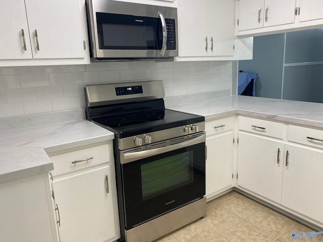 kitchen with white cabinetry, appliances with stainless steel finishes, light tile patterned flooring, and tasteful backsplash