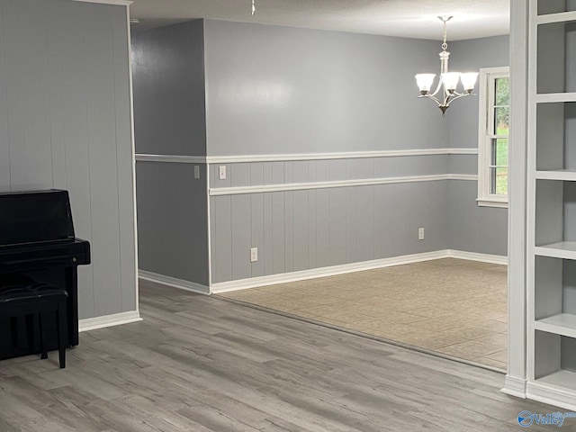 unfurnished dining area featuring wood walls, wood-type flooring, a textured ceiling, and a chandelier