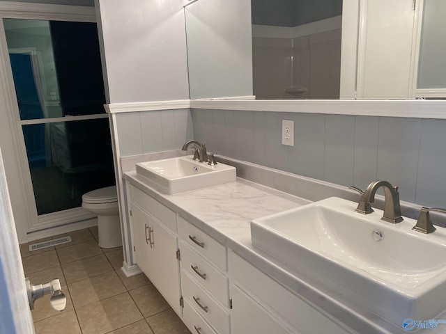 bathroom with vanity, tile patterned floors, toilet, and a shower