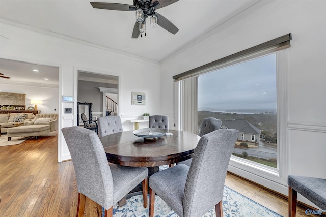 dining space with crown molding, wood-type flooring, and ceiling fan