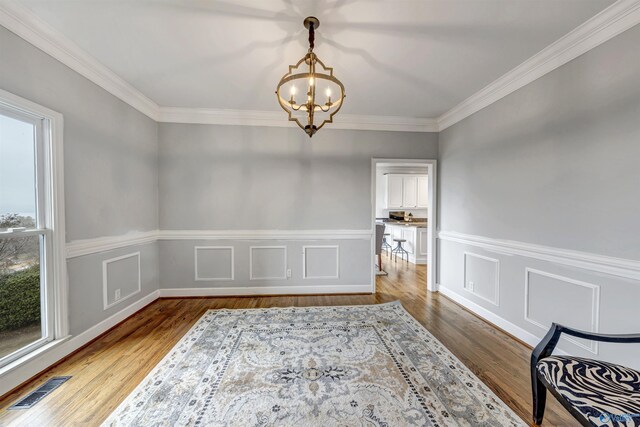 dining area featuring hardwood / wood-style flooring, ornamental molding, and an inviting chandelier