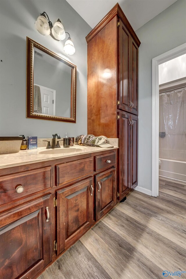 bathroom featuring vanity, hardwood / wood-style floors, and bathing tub / shower combination