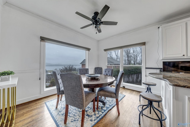 dining space with light hardwood / wood-style flooring, ornamental molding, and ceiling fan