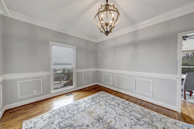 unfurnished room featuring ornamental molding, wood-type flooring, and a notable chandelier