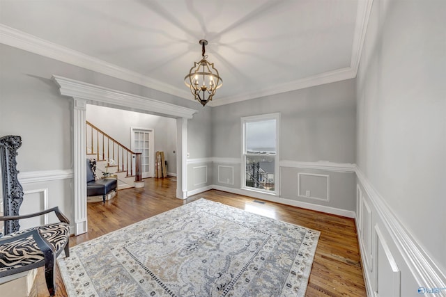 living room featuring hardwood / wood-style flooring, ornamental molding, and an inviting chandelier