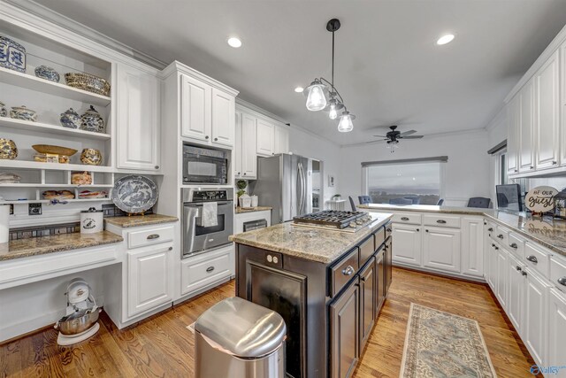 kitchen featuring appliances with stainless steel finishes, white cabinets, light wood-type flooring, and decorative light fixtures