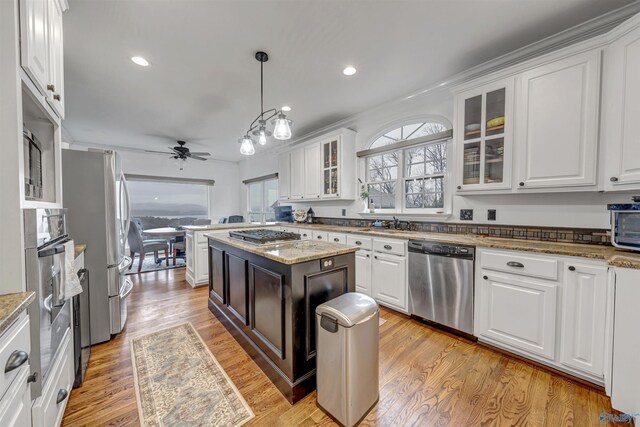 kitchen featuring white cabinetry, stainless steel appliances, light stone counters, and pendant lighting