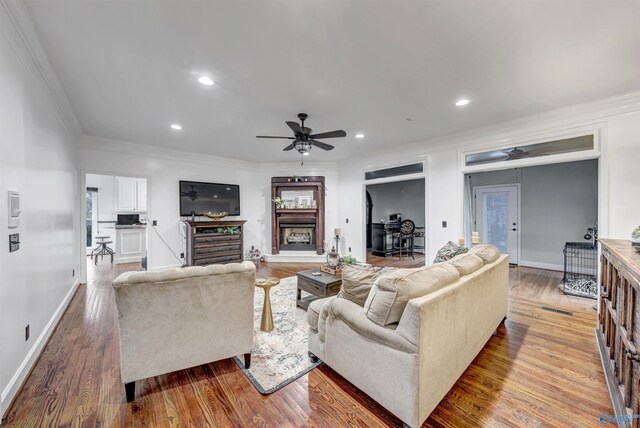 living room featuring ceiling fan, ornamental molding, and light hardwood / wood-style floors