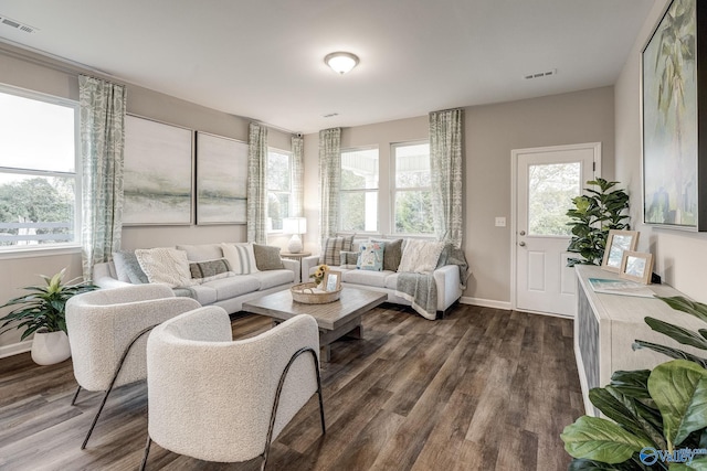 living room with dark wood-style floors, visible vents, and baseboards