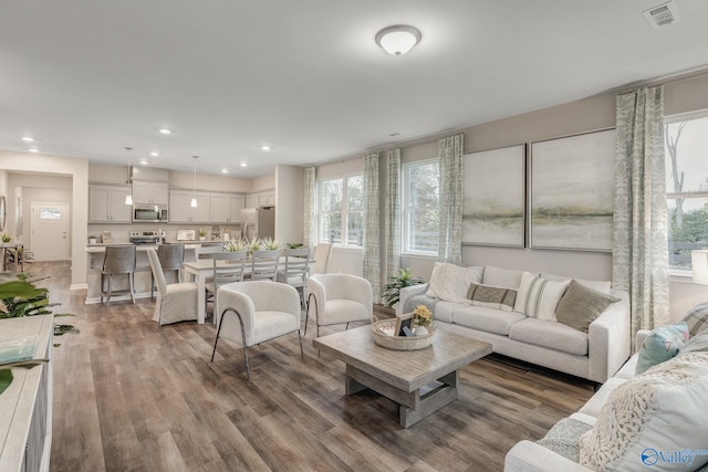 living room with recessed lighting, visible vents, and wood finished floors