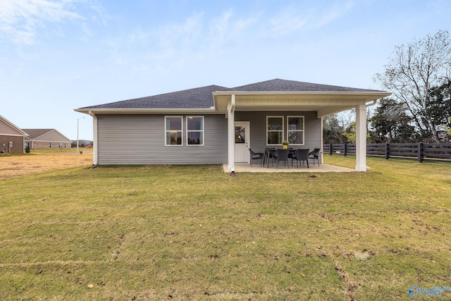 rear view of property with a yard, a patio, a shingled roof, and fence