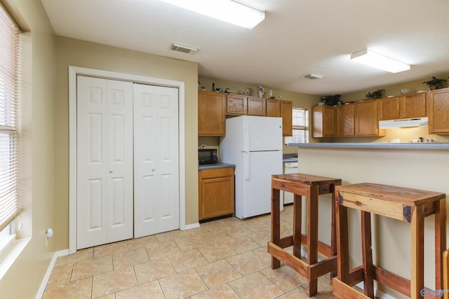 kitchen with light tile patterned floors and white refrigerator