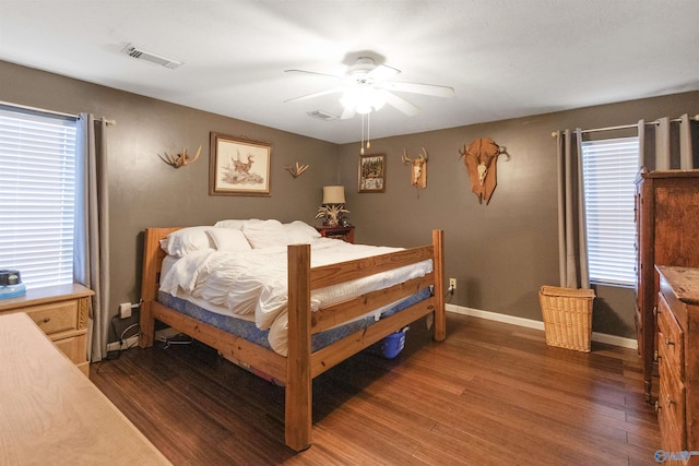 bedroom with multiple windows, dark wood-type flooring, and ceiling fan