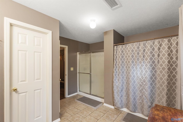 bathroom with tile patterned flooring, a textured ceiling, and walk in shower