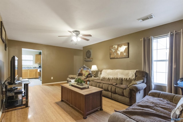 living room featuring a healthy amount of sunlight, ceiling fan, and light hardwood / wood-style flooring