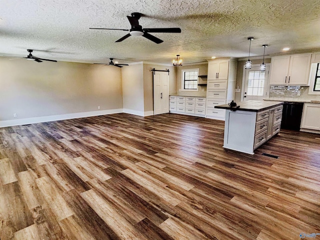 kitchen with a barn door, ceiling fan, and dark wood-style flooring