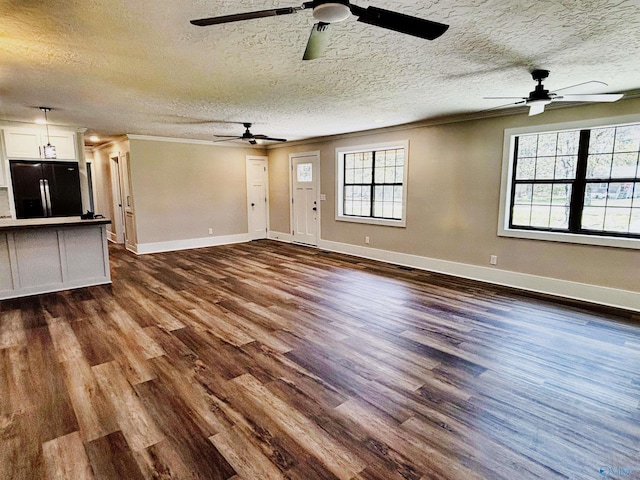 unfurnished living room with a textured ceiling, dark wood-style floors, ceiling fan, and baseboards