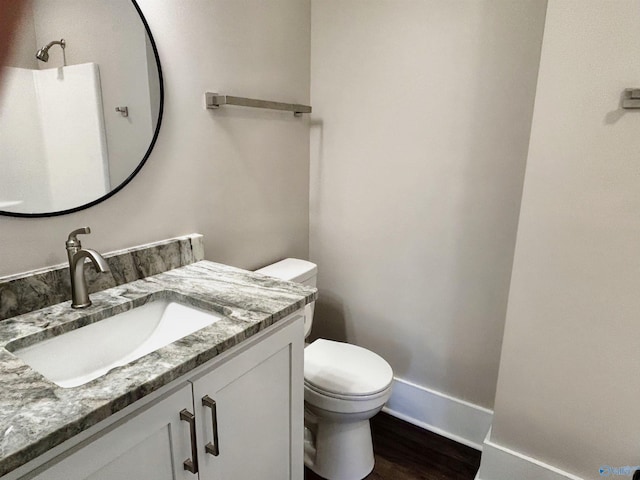 bathroom featuring toilet, vanity, baseboards, and wood finished floors