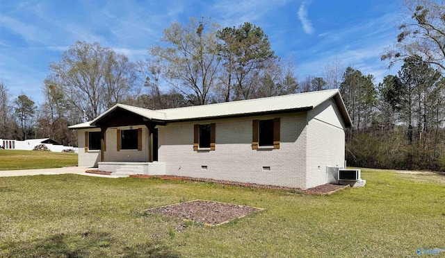 ranch-style home featuring central air condition unit, metal roof, a front yard, and brick siding