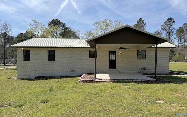 rear view of property with a lawn, a patio, brick siding, and a ceiling fan