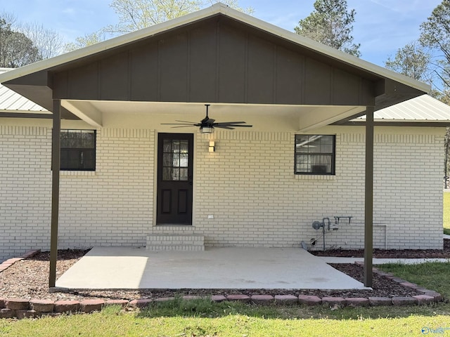 doorway to property with brick siding, metal roof, a patio area, and ceiling fan