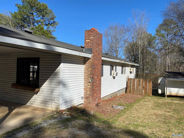 view of home's exterior with a lawn, a chimney, an outdoor structure, and a storage unit