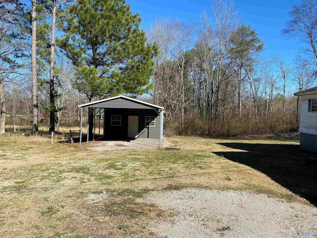 view of yard featuring a detached carport, driveway, and an outdoor structure