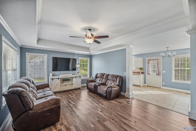 living room with hardwood / wood-style floors, ceiling fan with notable chandelier, and ornamental molding