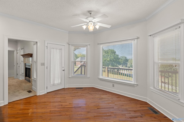 spare room with a textured ceiling, a wealth of natural light, ceiling fan, and hardwood / wood-style flooring