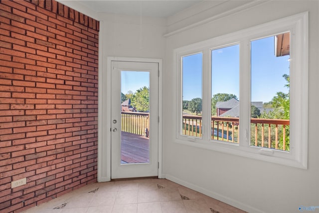 doorway featuring brick wall and light tile patterned floors