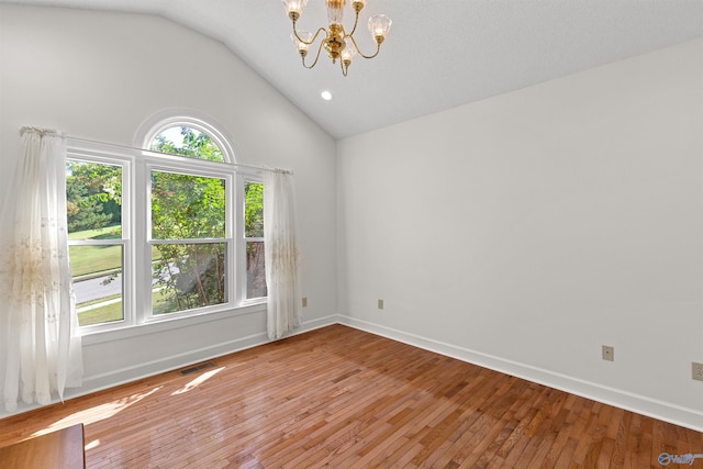 empty room featuring vaulted ceiling, a notable chandelier, hardwood / wood-style floors, and a textured ceiling