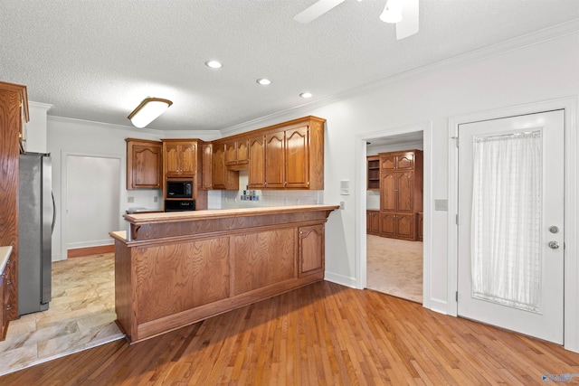 kitchen featuring light wood-type flooring, black appliances, kitchen peninsula, and ceiling fan