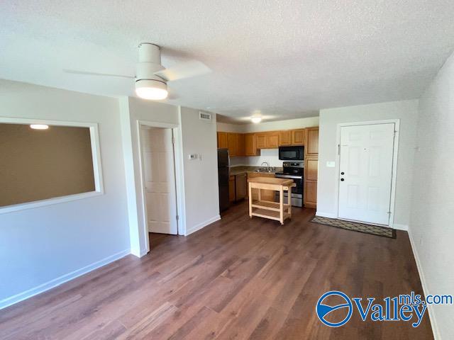 kitchen featuring ceiling fan, a breakfast bar, black appliances, and dark hardwood / wood-style floors