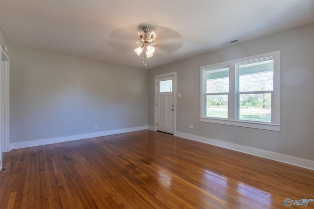 interior space featuring a textured ceiling, ceiling fan, and dark wood-type flooring